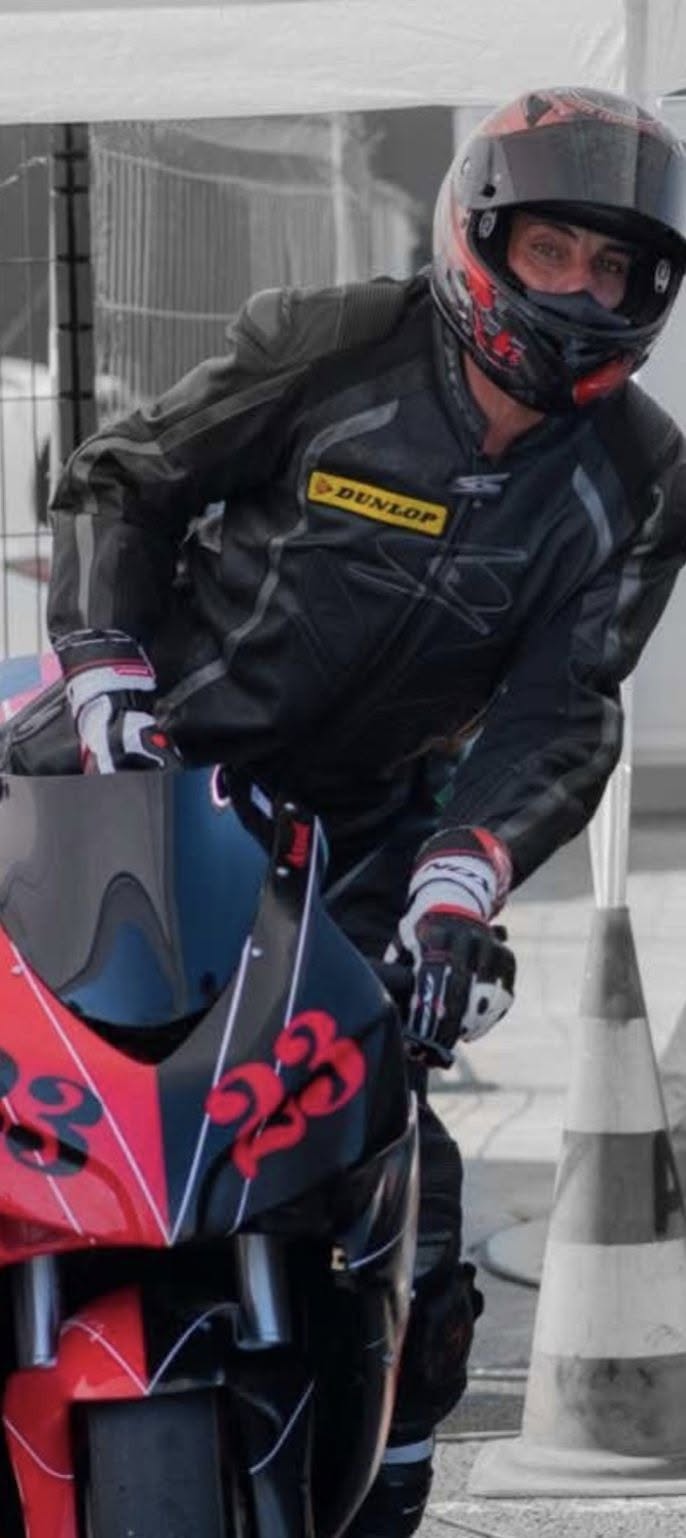 Axel Broutin en tenue de pilote et casque, sur sa moto de course rouge et noire
